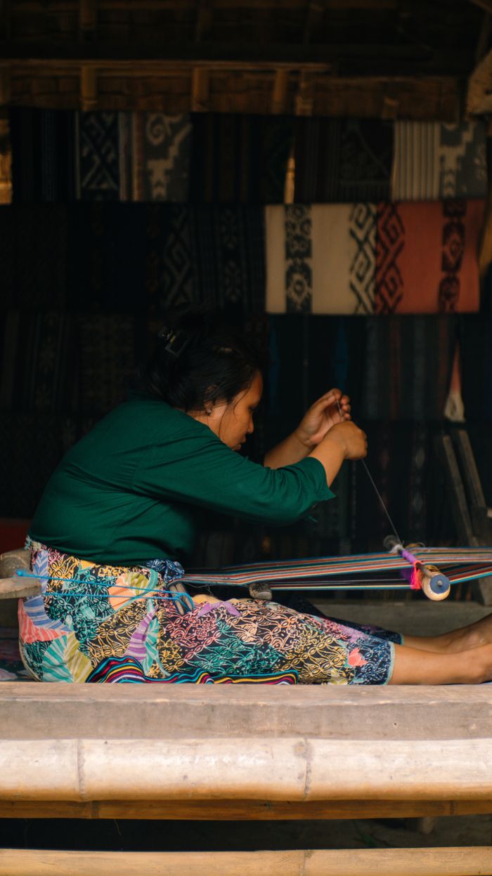 Cultural portrait of a textile weaver in traditional attire, crafting on a loom.