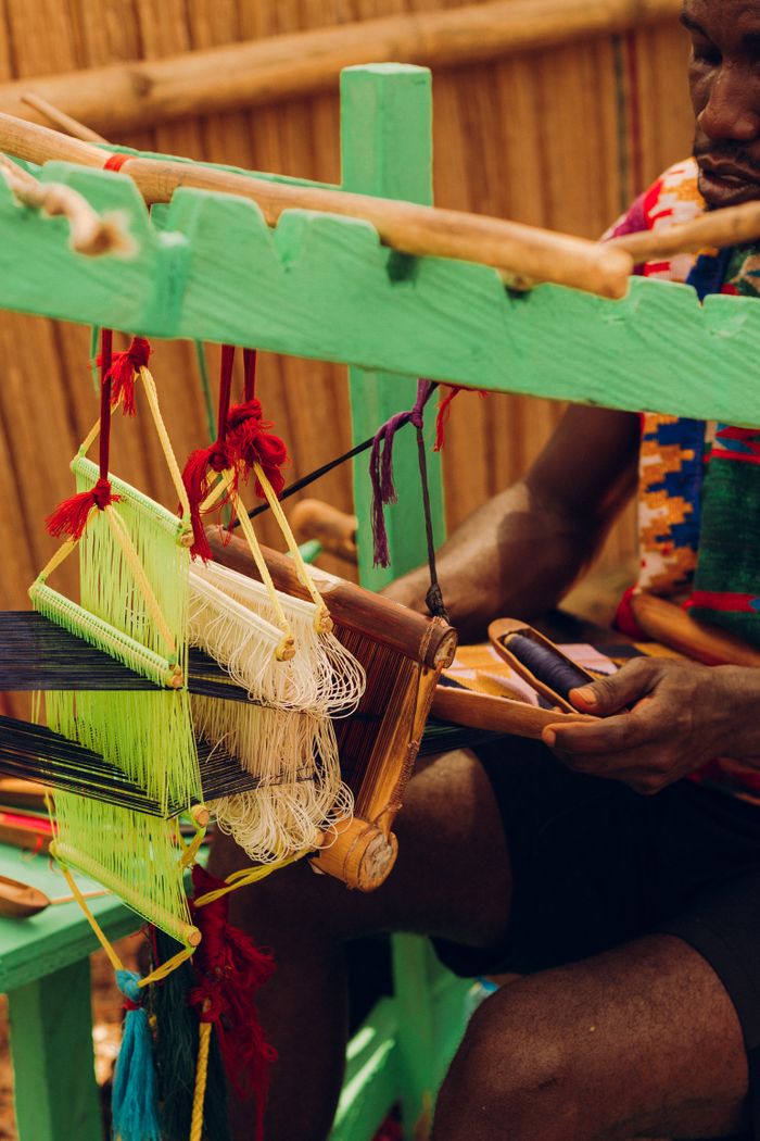 A craftsman weaves colorful Kente cloth on a traditional loom in Accra, Ghana.