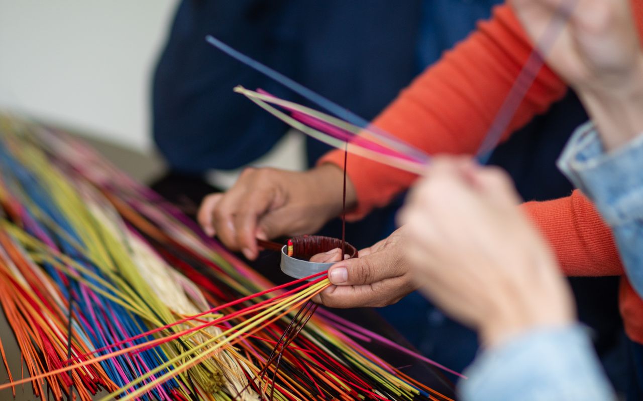Close-up of hands weaving vibrant, multicolored threads in Piura, Peru, showcasing traditional craftsmanship.